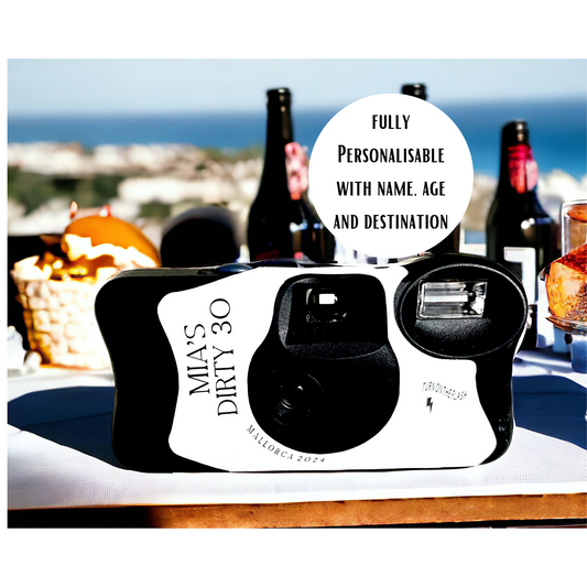 A Kodak polaroid disposable camera sticker personalised for a 30th birthday destination weekend break away. Shown on a table with wine and food with the sea in the background.